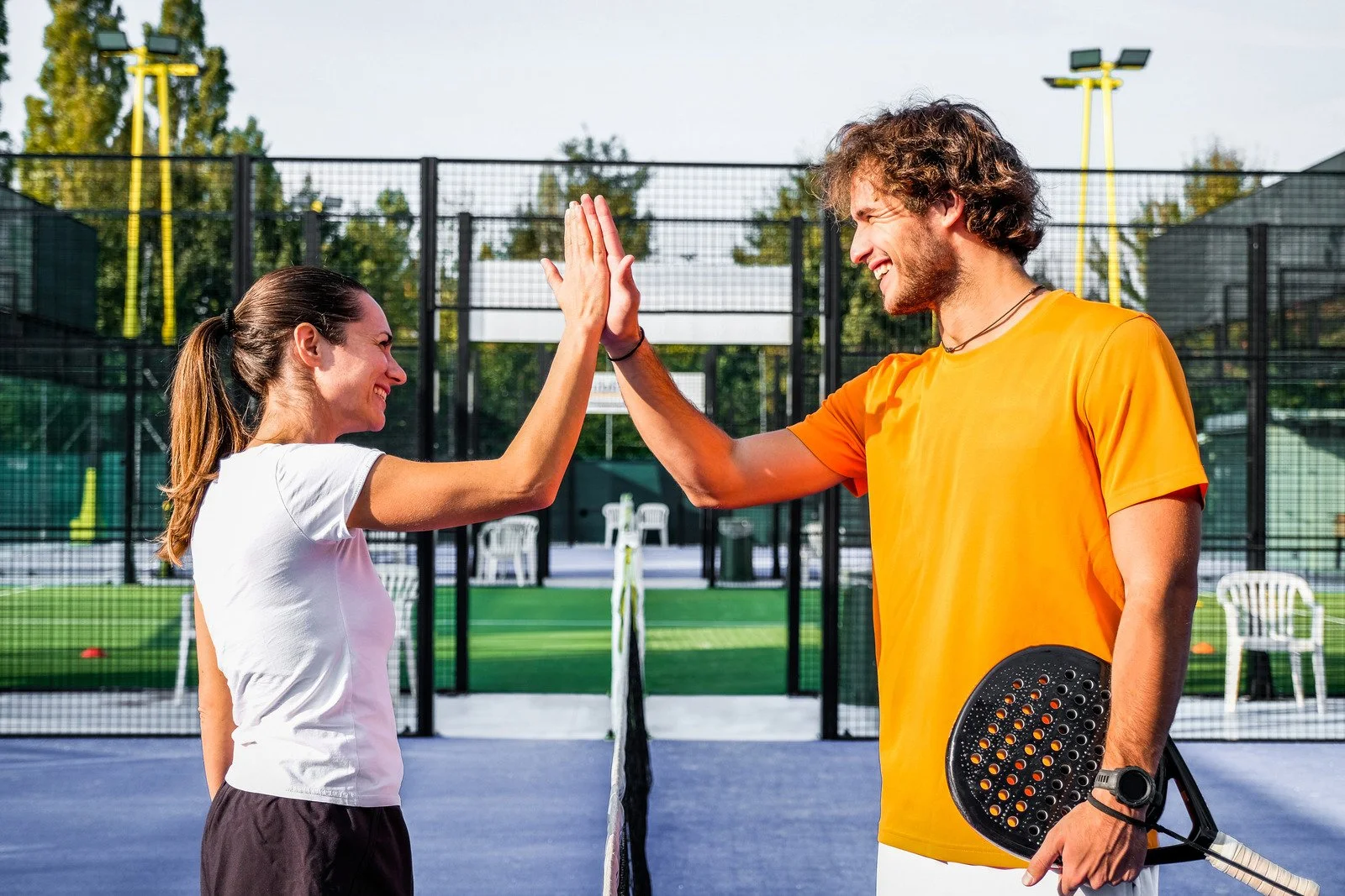 Deux partenaires de padel se tapant la main sur un terrain - Cours de padel